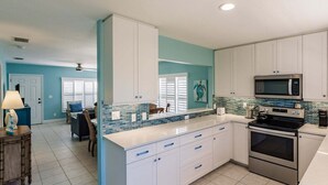 A kitchen with white cabinets, a blue backsplash, and stainless steel appliances. - Villa 02 - Premium Plus - Aloha Kai Vacation Villas (Siesta Key)