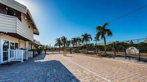 A paved walkway leading to a building with a sign reading 'Aloha Kai Entrance'. - Villa 02 - Premium Plus - Aloha Kai Vacation Villas (Siesta Key)