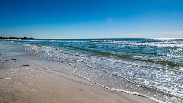 A beach with waves, a clear sky, and a distant shoreline. - Villa 02 - Premium Plus - Aloha Kai Vacation Villas (Siesta Key)