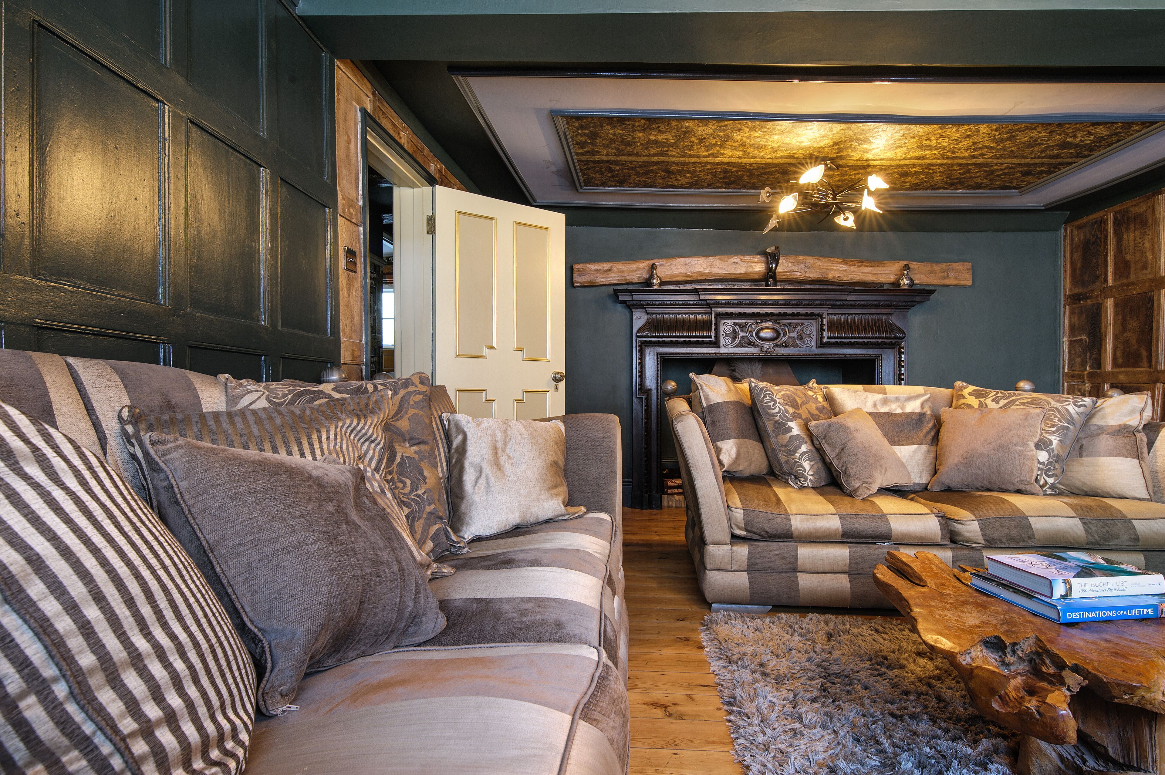 A cozy living room with a sofa and armchair, a fireplace, and a rustic coffee table.
