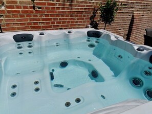 A hot tub with multiple jets, set against a brick wall. - Luxury 2 Bed Manor House Hot Tub Cinema Room Skytv (Saffron Walden)