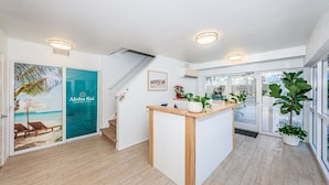 Eine moderne Hotellobby mit einer Rezeption, einer Treppe und einem großen Fenster mit Blick ins Freie.