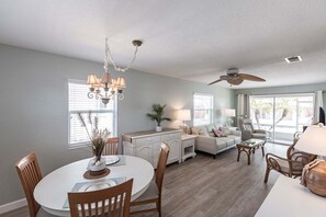 A spacious living area with a dining table, sofas, and a ceiling fan.