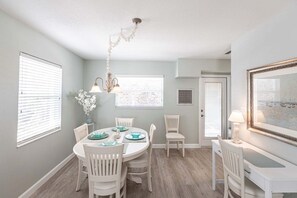 A dining area with a round table, white chairs, and a chandelier.