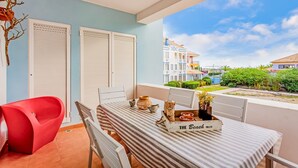 A balcony with a striped table, chairs, and a red chair. - Golden 1 BDR Flat W/ Balcony & Pool by LovelyStay (Cabanas)