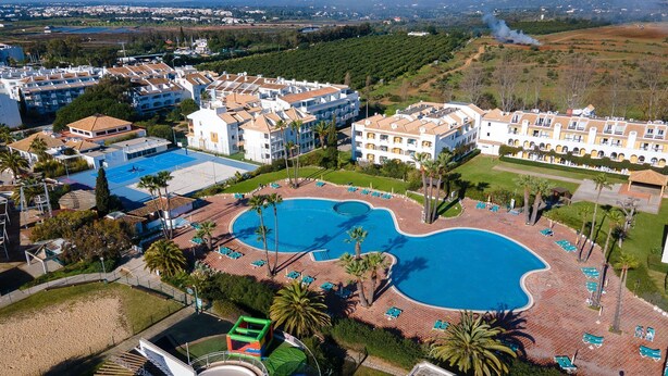 A resort with a large swimming pool, multiple buildings, and a view of the surrounding landscape. - Golden 1 BDR Flat W/ Balcony & Pool by LovelyStay (Cabanas)
