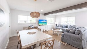 A modern living room with a dining area, a television, and a large window. - Villa 27 - Premium Plus (Siesta Key)