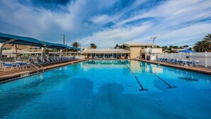 A swimming pool with lounge chairs and umbrellas, surrounded by buildings and palm trees. - Villa 27 - Premium Plus (Siesta Key)