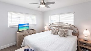 A bedroom with a bed, a ceiling fan, a TV, and a nightstand with a lamp. - Villa 27 - Premium Plus (Siesta Key)