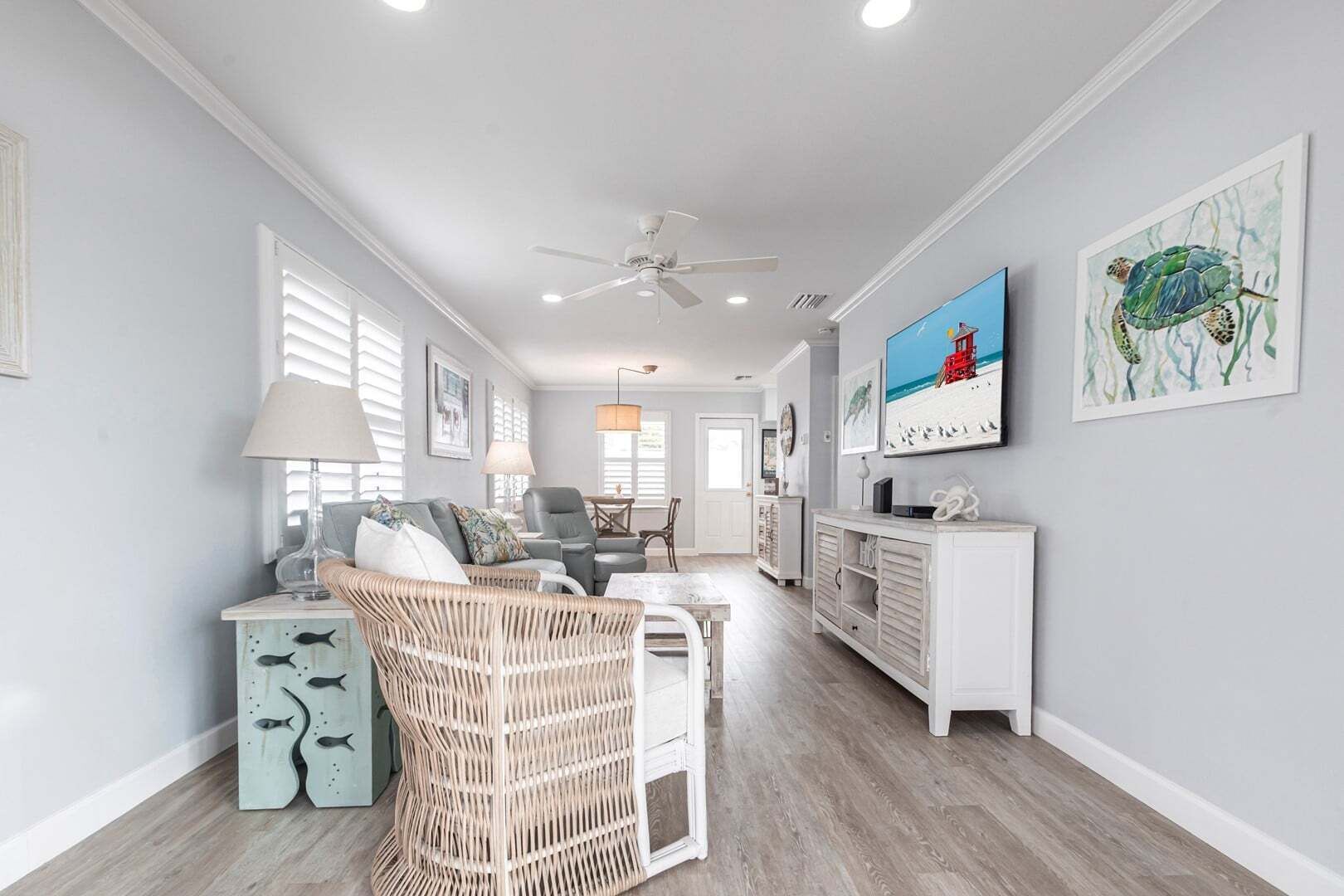 A spacious living room with a ceiling fan, a television, and artwork on the walls.