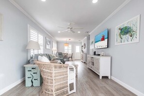 A spacious living room with a ceiling fan, a television, and artwork on the walls.