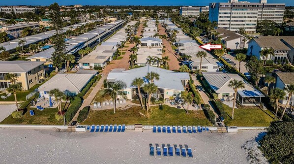 A resort with multiple villas, a central pool area, and a beach with sun loungers.
