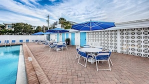 A poolside area with lounge chairs and umbrellas, a pool, and a decorative fence. - Aloha Kai Villa 32 - Premium Siesta Key Beach (Siesta Key)