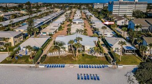 A resort with multiple villas, a central pool area, and a beach with sun loungers.