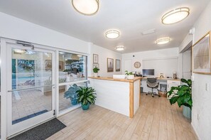 Un área de recepción con un mostrador, computadora y zona de estar.