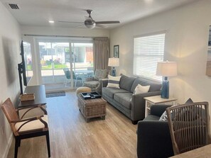 A living room with a sofa, chairs, a coffee table, a lamp, and a ceiling fan.
