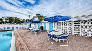 A poolside area with lounge chairs and umbrellas, a pool, and a white lattice fence. - Villa 38 - Premium - Aloha Kai Vacation Villas (Siesta Key)