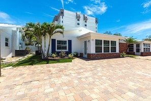 A modern two-story house with a brick exterior, a covered patio, and a well-maintained lawn.