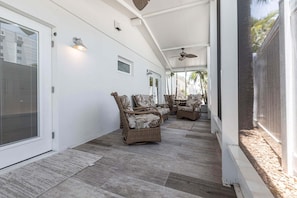 A covered patio area with wicker furniture, a ceiling fan, and a view of the outdoors.
