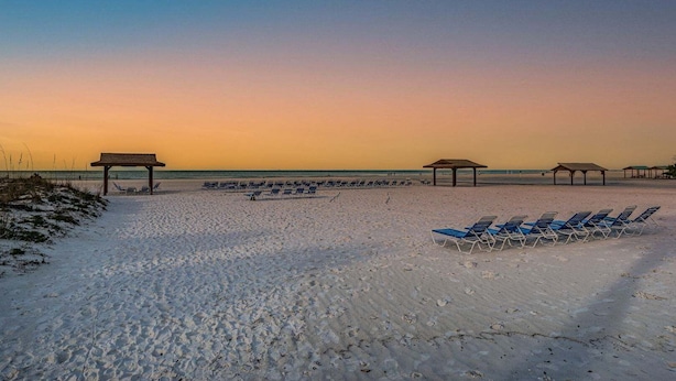 A beach with sun loungers and gazebos.