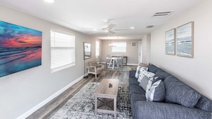 A spacious living room with a gray sofa, a coffee table, and a dining area with a table and chairs.