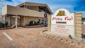 A two-story building with a stone facade and a sign for Aloha Kai Vacation Rentals.