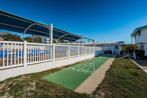 A pool area with a covered seating area, a shuffleboard court, and a fenced poolside. - Villa 48 - Preium Plus (Siesta Key)
