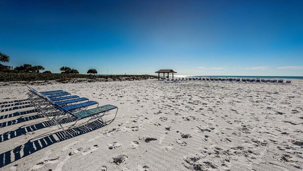 A beach with sun loungers and a pavilion.
