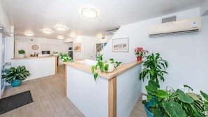 Een moderne keuken met een centraal eiland, witte keukenkastjes en meerdere plafondlampen.