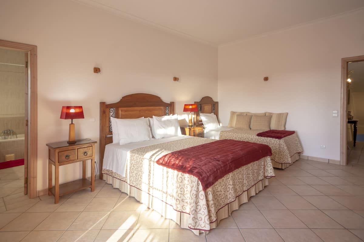 A hotel room with two beds, a wooden nightstand, a red lamp, and a mirror.