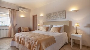 A bedroom with a large bed, two bedside tables, a window with curtains, and a wall-mounted air conditioner. - Al Meida Guesthouse (Albufeira)