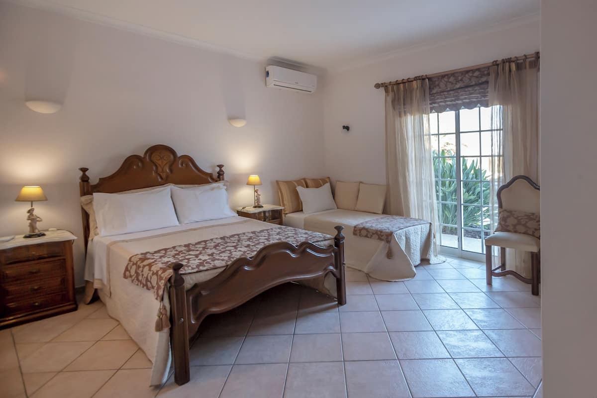 A bedroom with two beds, a nightstand, a chair, and a window with curtains.