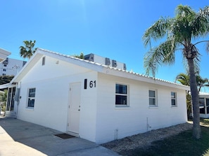 A single-story building with a white exterior, numbered 61, featuring a front door and windows.