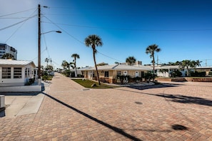 A residential street with houses, palm trees, and a clear sky.
