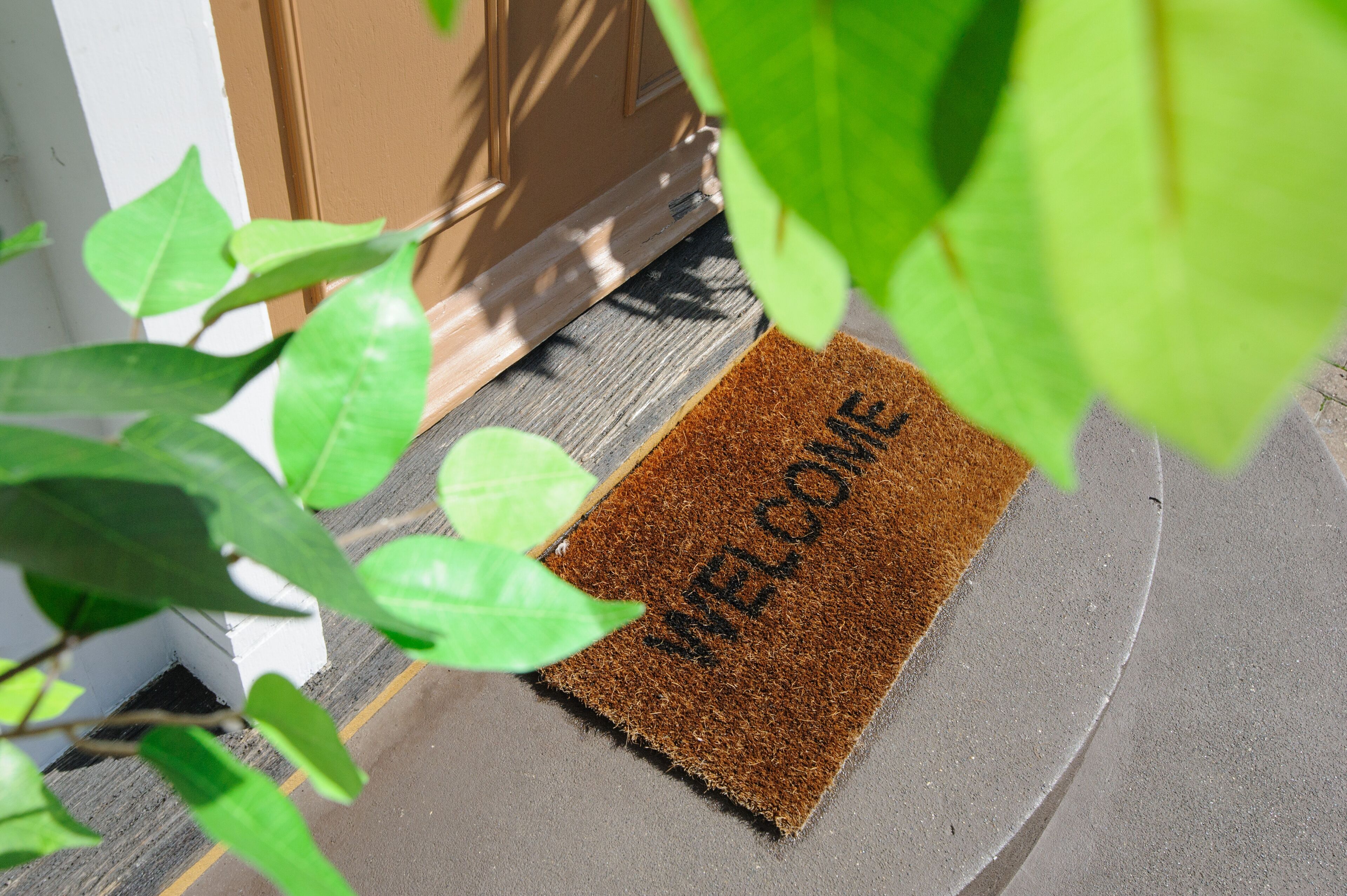A brown doormat with "WELCOME" written on it, placed at the entrance of a building.
