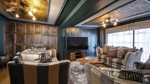 A living room with a large TV, a sofa, and a coffee table. - Luxury 3 Bed Manor House Hot Tub Cinema Room Skytv (Saffron Walden)
