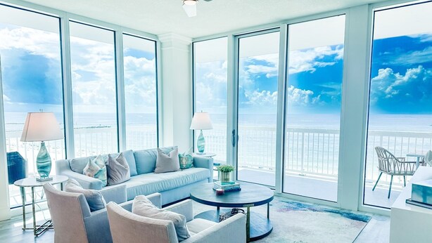A spacious room with a large window overlooking the ocean. There is a sofa, a coffee table, and a chair. - Unwind by the Beach in Orange Beach! 4 bed/3bath - Sleeps 8 - Oceanfront View (Orange Beach)