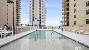 A swimming pool with a white fence, surrounded by high-rise buildings. - Unwind by the Beach in Orange Beach! 4 bed/3bath - Sleeps 8 - Oceanfront View (Orange Beach)
