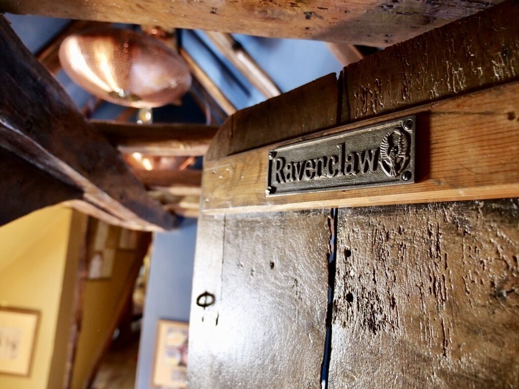 Un cartello di legno con il nome 'Ravenclaw' su una trave di legno rustica.