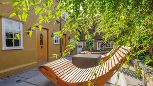 A hammock under a tree in a courtyard with a building in the background. - Luxury 8 Bed Manor House Hot Tub Cinema Room Skytv (Saffron Walden)