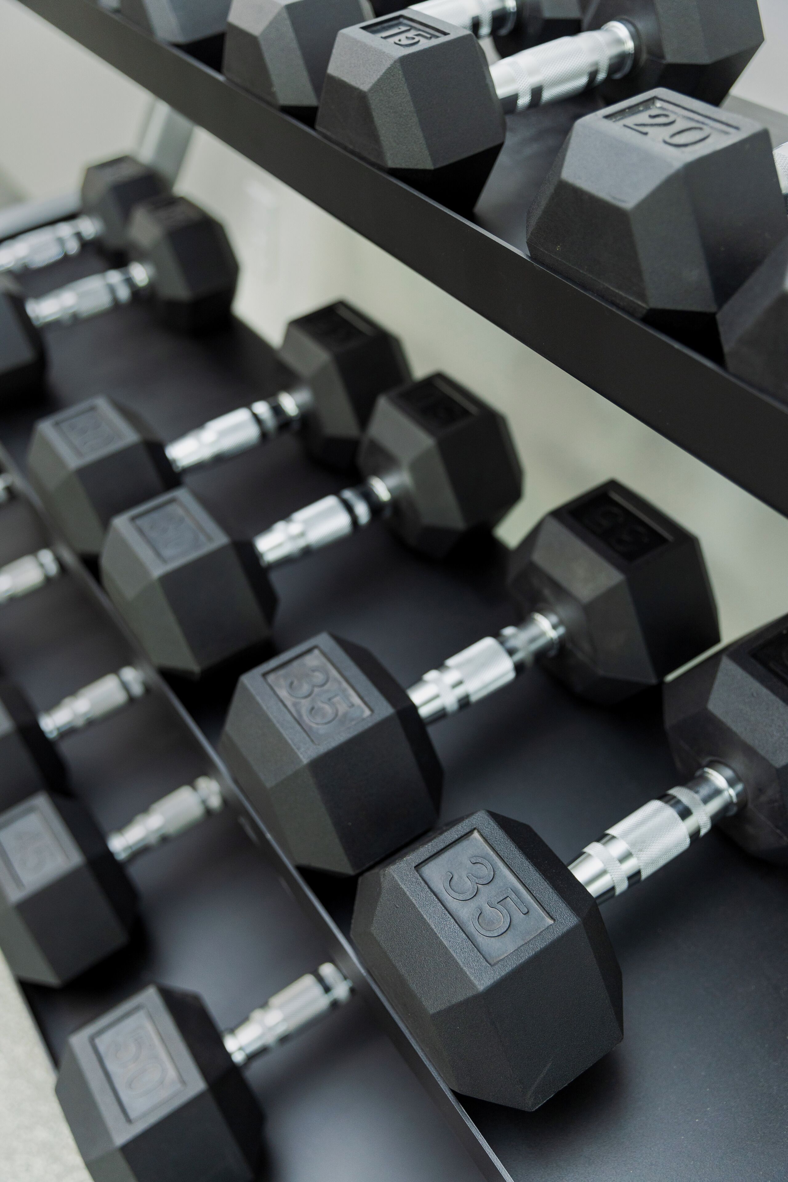 A rack of black dumbbells with visible weight markings.