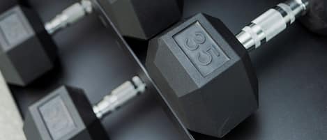 A rack of black dumbbells with visible weight markings.