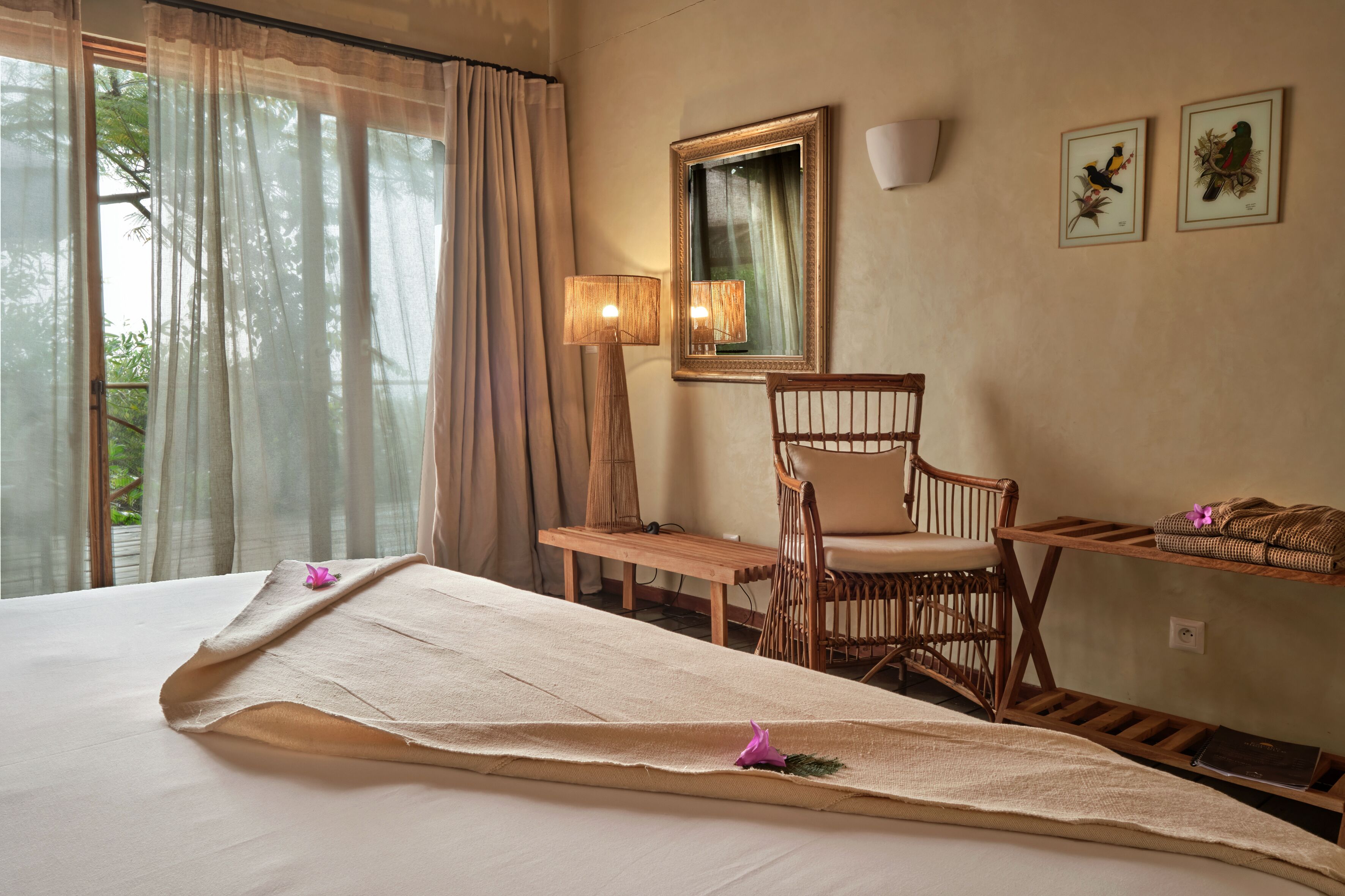 Una habitación de hotel con una cama, una silla, un escritorio, un espejo y dos cuadros en la pared.
