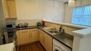 A compact kitchen with a washing machine, a microwave, and a toaster. - Apt Sleeps5-parkg-netflix-near City Centre/etihad (Manchester)
