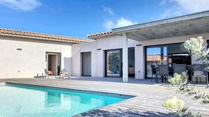 Ein modernes Haus mit Swimmingpool, Terrasse und Essbereich.