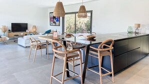 Eine moderne Küche mit Kochinsel, Barhocker und Pendelleuchten.