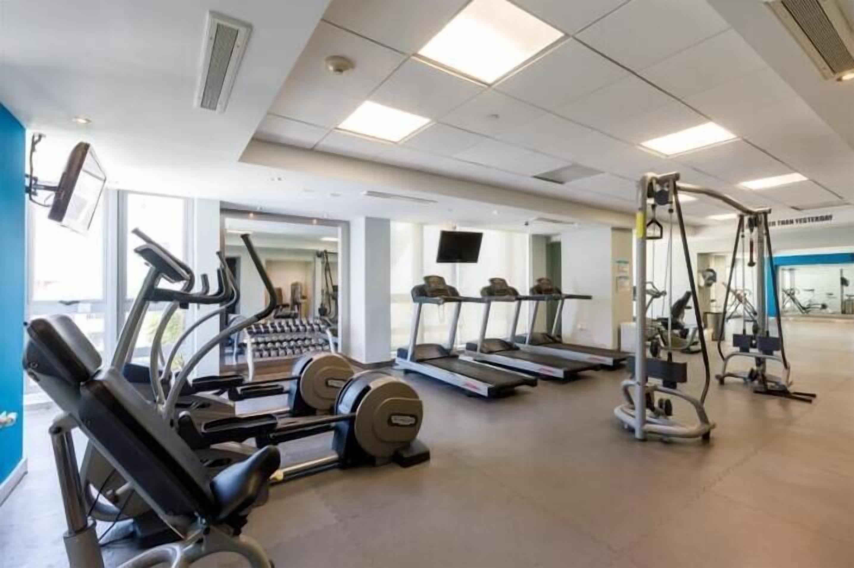 Ein Fitnessstudio mit Laufbändern, Crosstrainern und Gewichteinrichtungen.