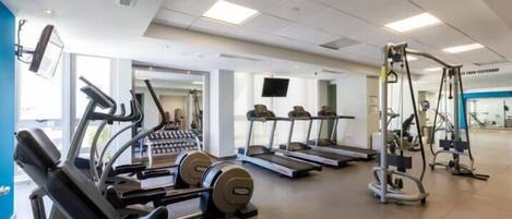 Ein Fitnessstudio mit Laufbändern, Crosstrainern und Gewichteinrichtungen.