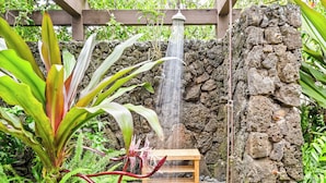 Um muro de pedra com uma pérgula de madeira e um banco de madeira.