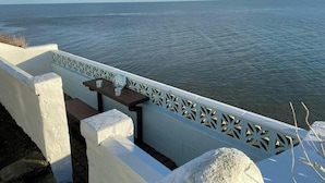 A balcony with a view of the sea, a white railing, and a table with two cups. - Min y Graig, New Quay (New Quay)